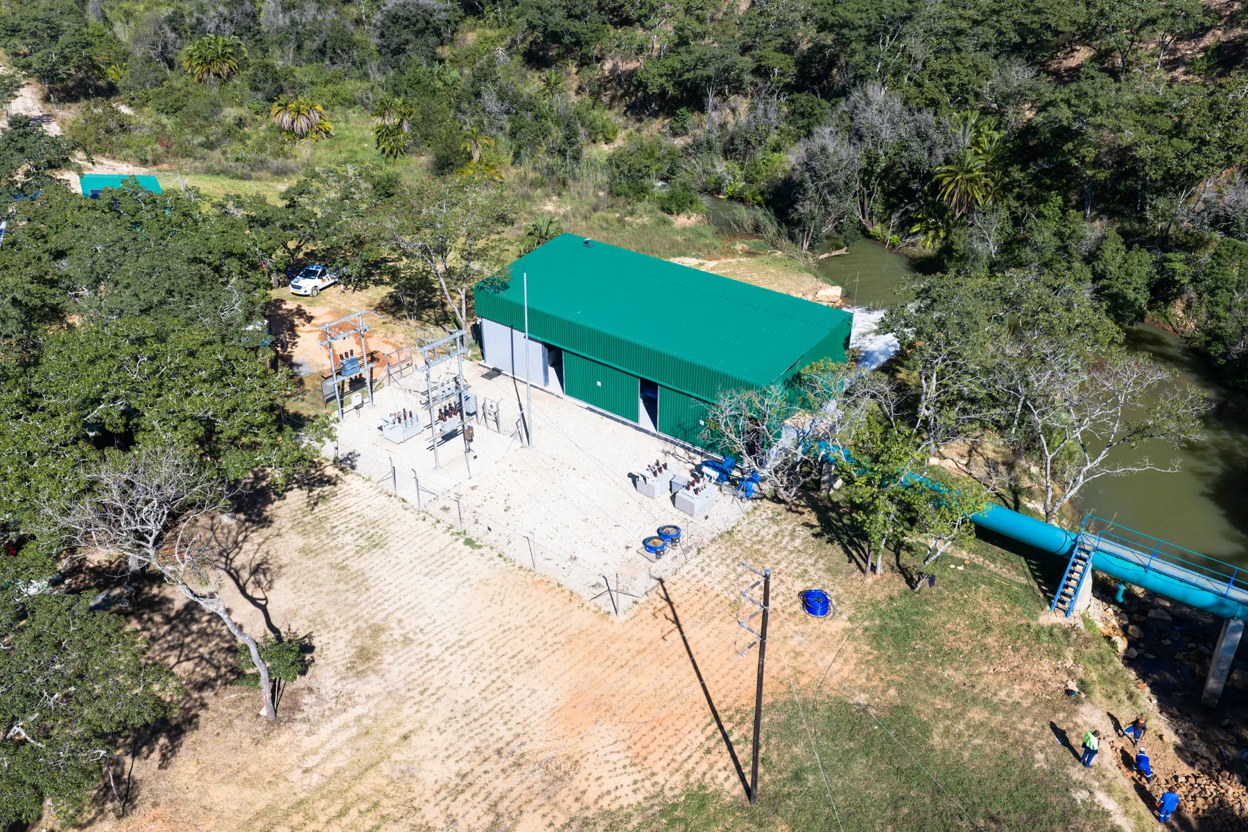 Aerial view of the Odzani powerhouse with its penstock running down to the river